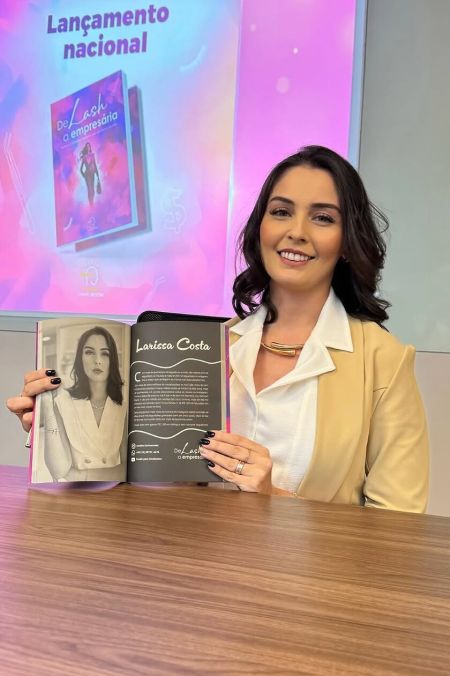 Larissa Costa sorrindo com seu livro sobre emprendedorismo